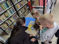Dzieci-z-pomoca-bibliotekarza-dekoruja-liscmi-papierowego-jezyka-scaled